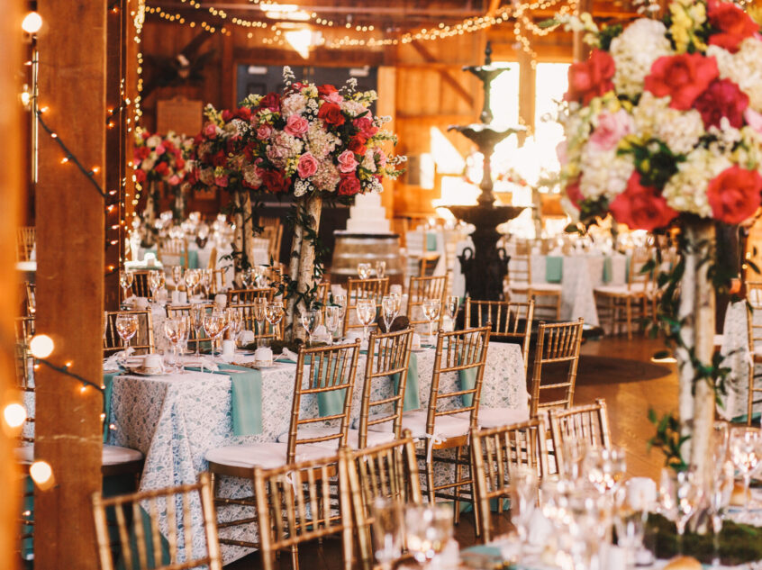 Rich dinner tables covered with blue clothes and sparkling glasswares stand in the wooden hangar