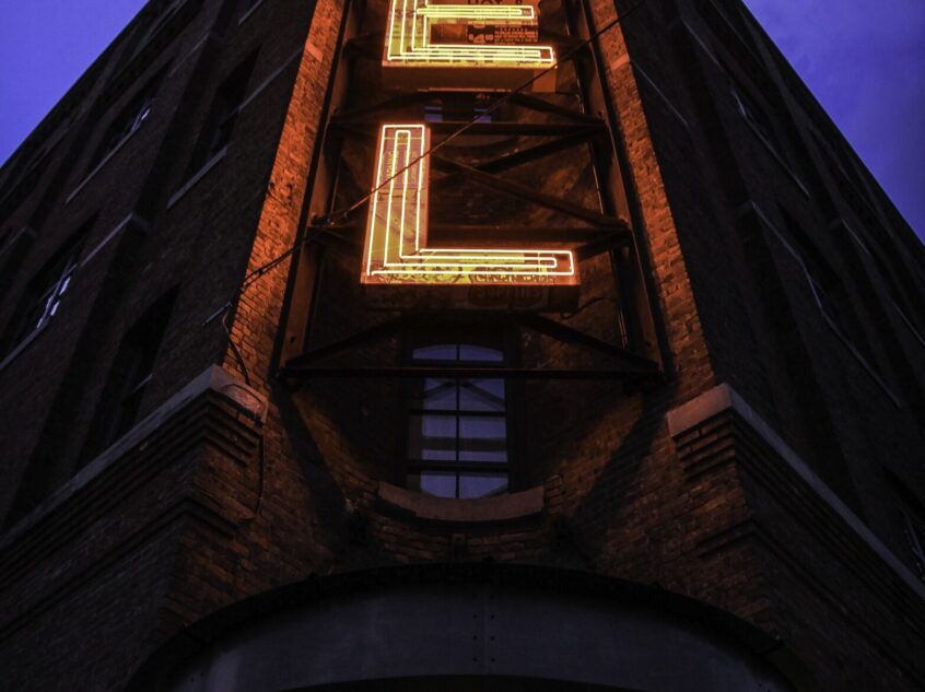 A vertical shot of a big building with a hotel sign and a dark blue sky in the background
